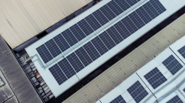 Bir binanın çatısına birden fazla güneş paneli yerleştirildi. Güneş panelleri düzenli sıra ve sütunlar halinde düzenlenir, her panel arasında net ayrılıklar bulunur. 