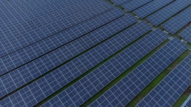 Bir binanın çatısına birden fazla güneş paneli yerleştirildi. Güneş panelleri düzenli sıra ve sütunlar halinde düzenlenir, her panel arasında net ayrılıklar bulunur. 