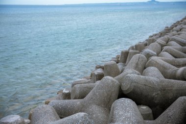 Okinawa sahilinin atmosferinde kristal berrak su, görünür kayalar ve kıyıya vuran dalgalar vardır..