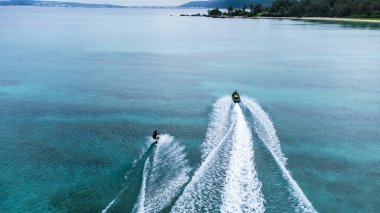 Okinawa sahilinin atmosferinde kristal berrak su, görünür kayalar ve kıyıya vuran dalgalar vardır..