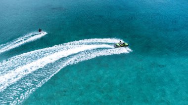 Okinawa sahilinin atmosferinde kristal berrak su, görünür kayalar ve kıyıya vuran dalgalar vardır..