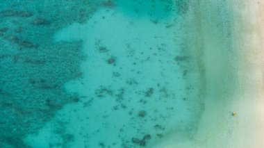 Okinawa sahilinin atmosferinde kristal berrak su, görünür kayalar ve kıyıya vuran dalgalar vardır..