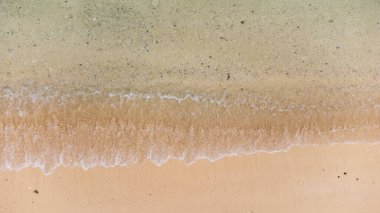 Okinawa sahilinin atmosferinde kristal berrak su, görünür kayalar ve kıyıya vuran dalgalar vardır..