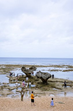 Okinawa sahilinin atmosferinde kristal berrak su, görünür kayalar ve kıyıya vuran dalgalar vardır..