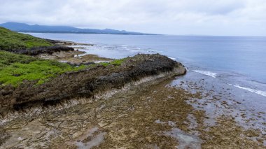 Okinawa 'da deniz yüzeyi temiz su ve insansız hava aracının öfke bakışından kayayla kaplı..