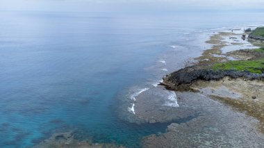 Okinawa 'da deniz yüzeyi temiz su ve insansız hava aracının öfke bakışından kayayla kaplı..