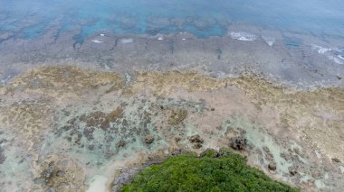 Okinawa 'da deniz yüzeyi temiz su ve insansız hava aracının öfke bakışından kayayla kaplı..
