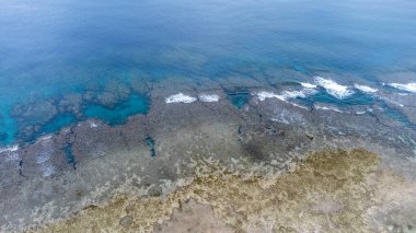 Okinawa 'da deniz yüzeyi temiz su ve insansız hava aracının öfke bakışından kayayla kaplı..