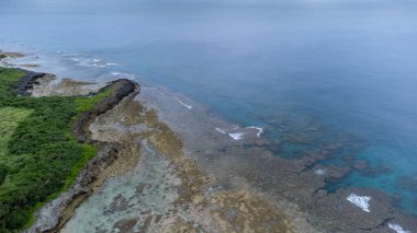 Okinawa 'da deniz yüzeyi temiz su ve insansız hava aracının öfke bakışından kayayla kaplı..