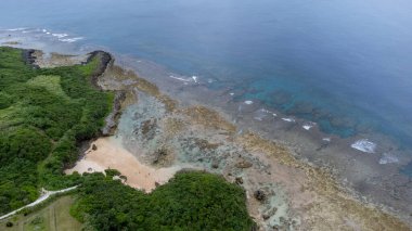 Okinawa 'da deniz yüzeyi temiz su ve insansız hava aracının öfke bakışından kayayla kaplı..