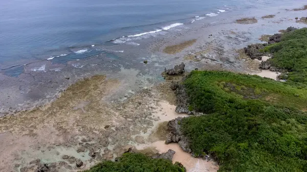 Okinawa 'da deniz yüzeyi temiz su ve insansız hava aracının öfke bakışından kayayla kaplı..
