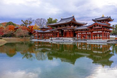 Kyoto, Japonya - Aralık 2024: Byodoin Tapınağı, UNESCO Dünya Mirasları Alanı, Uji, Kyoto. Resim, simetrik mimarisiyle ikonik Phoenix Salonu 'nu sergiliyor. Huzurlu gölete güzel yansıyor..