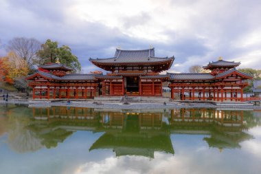 Kyoto, Japonya - Aralık 2024: Byodoin Tapınağı, UNESCO Dünya Mirasları Alanı, Uji, Kyoto. Resim, simetrik mimarisiyle ikonik Phoenix Salonu 'nu sergiliyor. Huzurlu gölete güzel yansıyor..