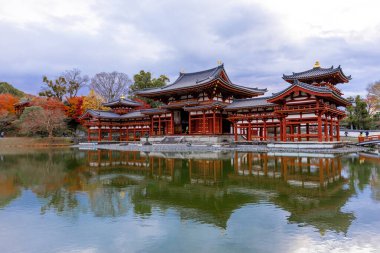 Kyoto, Japonya - Aralık 2024: Byodoin Tapınağı, UNESCO Dünya Mirasları Alanı, Uji, Kyoto. Resim, simetrik mimarisiyle ikonik Phoenix Salonu 'nu sergiliyor. Huzurlu gölete güzel yansıyor..