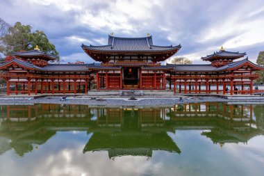 Kyoto, Japonya - Aralık 2024: Byodoin Tapınağı, UNESCO Dünya Mirasları Alanı, Uji, Kyoto. Resim, simetrik mimarisiyle ikonik Phoenix Salonu 'nu sergiliyor. Huzurlu gölete güzel yansıyor..