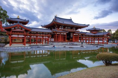 Kyoto, Japonya - Aralık 2024: Byodoin Tapınağı, UNESCO Dünya Mirasları Alanı, Uji, Kyoto. Resim, simetrik mimarisiyle ikonik Phoenix Salonu 'nu sergiliyor. Huzurlu gölete güzel yansıyor..