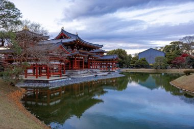 Kyoto, Japonya - Aralık 2024: Byodoin Tapınağı, UNESCO Dünya Mirasları Alanı, Uji, Kyoto. Resim, simetrik mimarisiyle ikonik Phoenix Salonu 'nu sergiliyor. Huzurlu gölete güzel yansıyor..