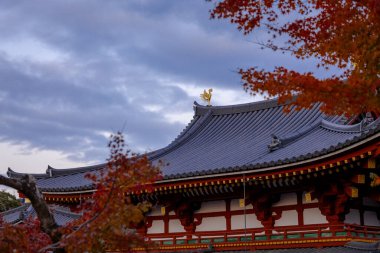 Kyoto, Japonya - Aralık 2024: Byodoin Tapınağı, UNESCO Dünya Mirasları Alanı, Uji, Kyoto. Resim, simetrik mimarisiyle ikonik Phoenix Salonu 'nu sergiliyor. Huzurlu gölete güzel yansıyor..
