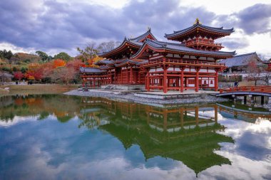 Kyoto, Japonya - Aralık 2024: Byodoin Tapınağı, UNESCO Dünya Mirasları Alanı, Uji, Kyoto. Resim, simetrik mimarisiyle ikonik Phoenix Salonu 'nu sergiliyor. Huzurlu gölete güzel yansıyor..