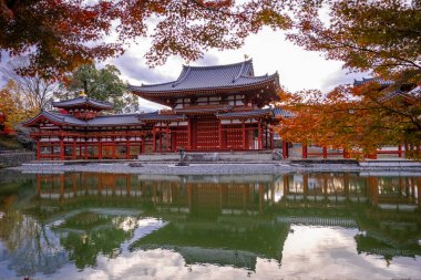 Kyoto, Japonya - Aralık 2024: Byodoin Tapınağı, UNESCO Dünya Mirasları Alanı, Uji, Kyoto. Resim, simetrik mimarisiyle ikonik Phoenix Salonu 'nu sergiliyor. Huzurlu gölete güzel yansıyor..