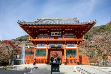 Osaka, Japonya - Aralık 2024: Minoh 'taki Katsuo-ji Tapınağı' nın en yoğun sonbahar dönemi manzarası. Canlı kırmızı ve turuncu akçaağaç yapraklarıyla güzelce çerçevelenmiş, Japon sonbaharının sakin atmosferini yansıtıyor..