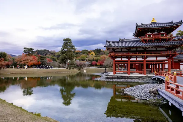 Kyoto, Japonya - Aralık 2024: Byodoin Tapınağı, UNESCO Dünya Mirasları Alanı, Uji, Kyoto. Resim, simetrik mimarisiyle ikonik Phoenix Salonu 'nu sergiliyor. Huzurlu gölete güzel yansıyor..