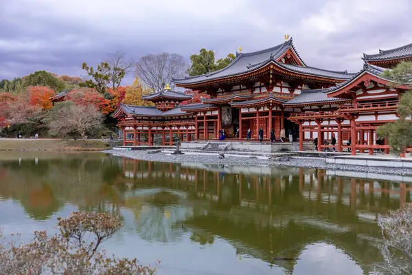 Kyoto, Japonya - Aralık 2024: Byodoin Tapınağı, UNESCO Dünya Mirasları Alanı, Uji, Kyoto. Resim, simetrik mimarisiyle ikonik Phoenix Salonu 'nu sergiliyor. Huzurlu gölete güzel yansıyor..