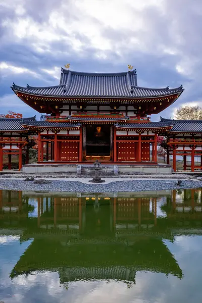 Kyoto, Japonya - Aralık 2024: Byodoin Tapınağı, UNESCO Dünya Mirasları Alanı, Uji, Kyoto. Resim, simetrik mimarisiyle ikonik Phoenix Salonu 'nu sergiliyor. Huzurlu gölete güzel yansıyor..