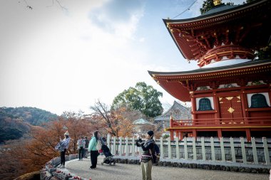 Osaka, Japonya - Aralık 2024: Minoh 'taki Katsuo-ji Tapınağı' nın en yoğun sonbahar dönemi manzarası. Canlı kırmızı ve turuncu akçaağaç yapraklarıyla güzelce çerçevelenmiş, Japon sonbaharının sakin atmosferini yansıtıyor..