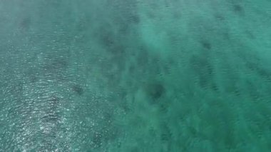 4K Okinawa 'nın sakin deniz manzarası kristal berrak suları, açıkta kayalık oluşumlar ve kıyıya vuran nazik dalgalar sergiliyor.