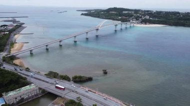4K Okinawa 'nın sakin deniz manzarası kristal berrak suları, açıkta kayalık oluşumlar ve kıyıya vuran nazik dalgalar sergiliyor.