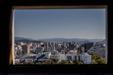 Kochi Şehri, Shikoku, Japonya - Aralık 2024: Kochi Kalesi canlı sonbahar yapraklarıyla çevrili iyi korunmuş bir Japon kalesidir. Ahşap yapının geleneksel kalesi kırmızı akçaağaç ve altın ginkgo ağaçları arasında zarif duruyor..