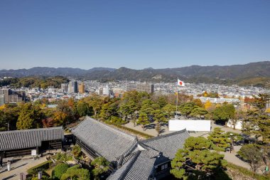 Kochi Şehri, Shikoku, Japonya - Aralık 2024: Kochi Kalesi canlı sonbahar yapraklarıyla çevrili iyi korunmuş bir Japon kalesidir. Ahşap yapının geleneksel kalesi kırmızı akçaağaç ve altın ginkgo ağaçları arasında zarif duruyor..