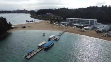 4K Okinawa 'nın sakin deniz manzarası üzerinde kristal berrak sular, açıkta kayalık oluşumlar ve kıyıya doğru hafif dalgalar.