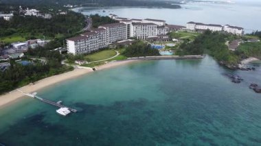 4K Okinawa 'nın sakin deniz manzarası üzerinde kristal berrak sular, açıkta kayalık oluşumlar ve kıyıya doğru hafif dalgalar.