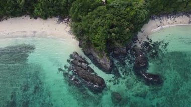 4K Okinawa 'nın sakin deniz manzarası üzerinde kristal berrak sular, açıkta kayalık oluşumlar ve kıyıya doğru hafif dalgalar.