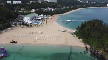 4K Okinawa 'nın sakin deniz manzarası üzerinde kristal berrak sular, açıkta kayalık oluşumlar ve kıyıya doğru hafif dalgalar.