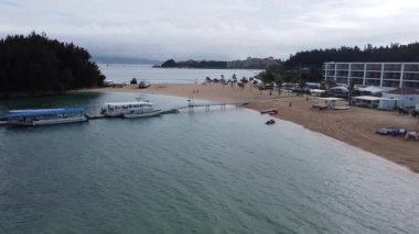 4K Okinawa 'nın sakin deniz manzarası üzerinde kristal berrak sular, açıkta kayalık oluşumlar ve kıyıya doğru hafif dalgalar.