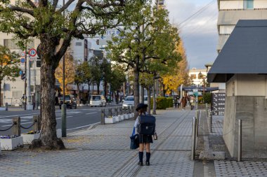 Japonya - Aralık 2024: Genç üniformalı Japon öğrenci okuldan sonra, geleneksel bir Randoseru sırt çantası taşıyarak tek başına kaldırımda yürüyor. Sahne Japonya 'daki günlük hayatın bir anını yakalar.