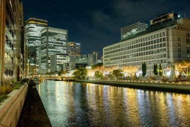 Osaka, Japonya - Aralık 2024: Osaka şehrinin canlı gece görüntüsü, Dotonbori veya Umeda gibi önemli bir bölge etrafında renkli aydınlatma ve neon ışıkları sergileniyor.