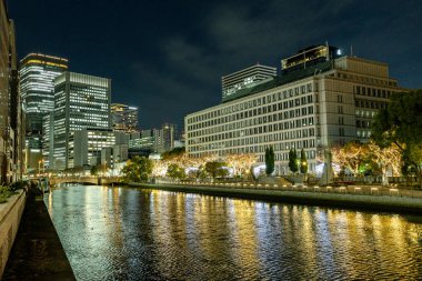 Osaka, Japonya - Aralık 2024: Osaka şehrinin canlı gece görüntüsü, Dotonbori veya Umeda gibi önemli bir bölge etrafında renkli aydınlatma ve neon ışıkları sergileniyor.