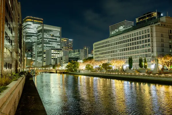 Osaka, Japonya - Aralık 2024: Osaka şehrinin canlı gece görüntüsü, Dotonbori veya Umeda gibi önemli bir bölge etrafında renkli aydınlatma ve neon ışıkları sergileniyor.
