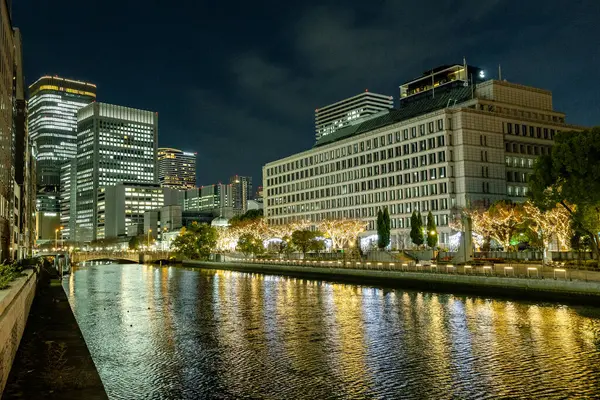 Osaka, Japonya - Aralık 2024: Osaka şehrinin canlı gece görüntüsü, Dotonbori veya Umeda gibi önemli bir bölge etrafında renkli aydınlatma ve neon ışıkları sergileniyor.