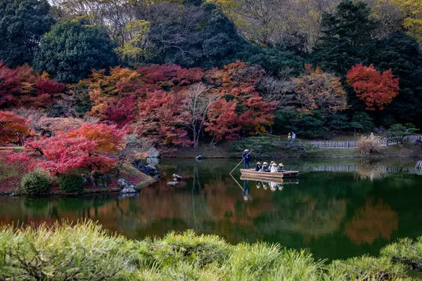 Kagawa, Japonya - Aralık 2024: Sonbahar sezonu boyunca Takamatsu 'daki Ritsurin Park' ın nefes kesici manzarası. Kırmızı ve turuncu renkli akçaağaç ağaçlarıyla geleneksel Japon bahçesi, sakin yansıtıcı havuzlar.