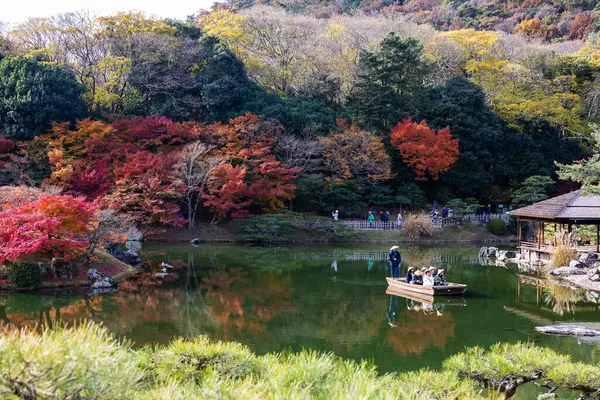 Kagawa, Japonya - Aralık 2024: Sonbahar sezonu boyunca Takamatsu 'daki Ritsurin Park' ın nefes kesici manzarası. Kırmızı ve turuncu renkli akçaağaç ağaçlarıyla geleneksel Japon bahçesi, sakin yansıtıcı havuzlar.