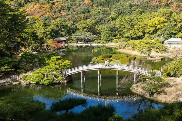 Takamatsu 'daki Ritsurin Parkı' nın sonbahar sezonunda nefes kesici manzarası. Kırmızı ve turuncu renkli akçaağaç ağaçlarıyla geleneksel Japon bahçesi, sakin yansıtıcı havuzlar.