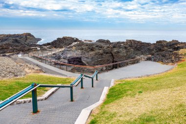 Kiama, NSW 'nin dışındaki Kiama hava deliğine giden adımlar. Avustralya. Havada 25 metreye kadar su püskürtebilen popüler hava deliği.