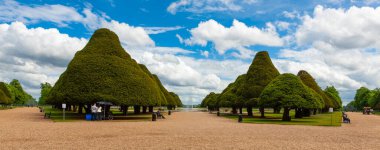 Hampton Sarayı 'nın Büyük Pınar Bahçesi. Düzgünce budanmış porsuk ağaçları doğudaki merkez çeşmeyi geçerek çakıl yayıyorlar..