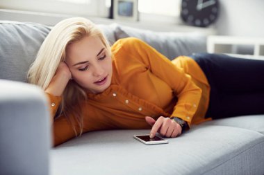 Genç kadın evde kanepede yalan onun smartphone cep telefonu ile internet tarama