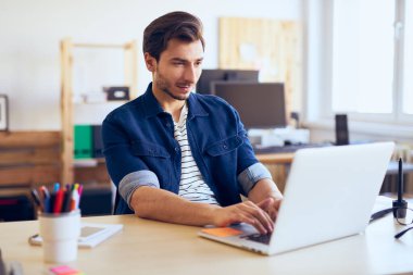 Yaratıcı ajans ofisinde dizüstü bilgisayarla çalışan adamlar.